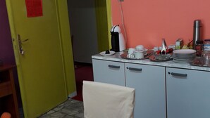 Une pièce comprenant une table à manger dressée, une chaise, un meuble contenant des appareils de cuisine et une porte avec une pancarte.