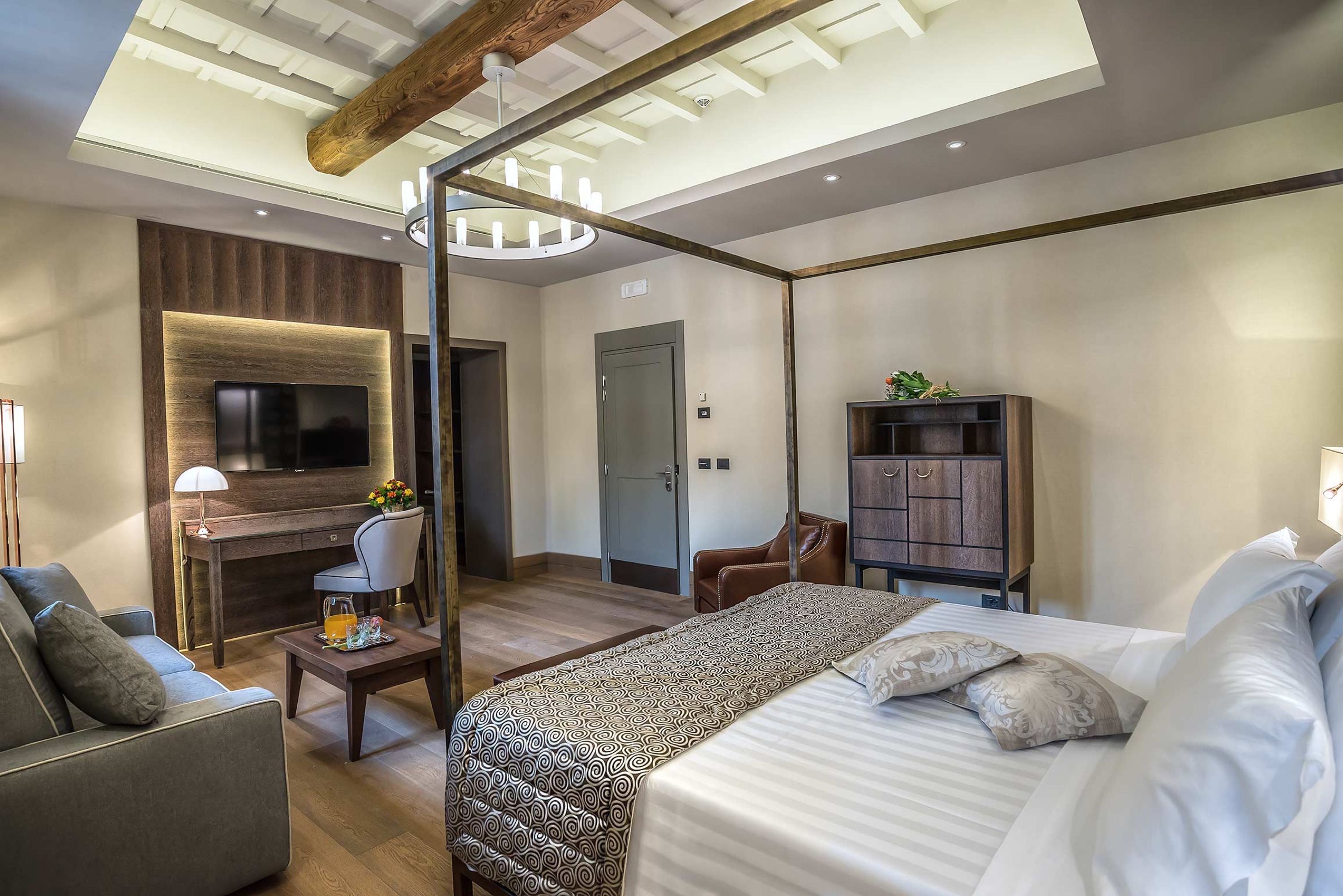 Una camera d'albergo moderna con un letto grande, una scrivania, una TV e un armadio.