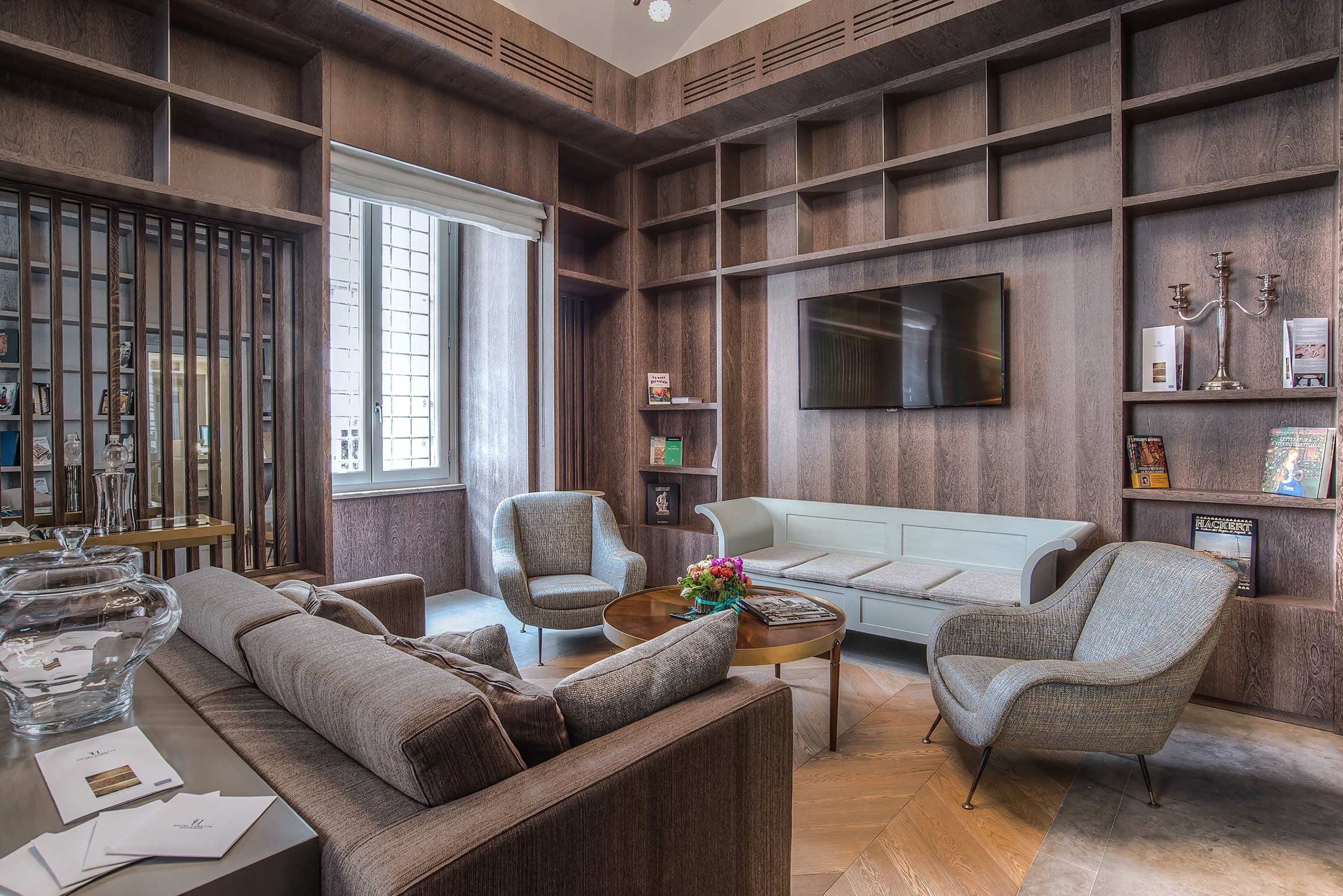 A modern living room with a sofa, armchairs, a coffee table, and a TV mounted on the wall.