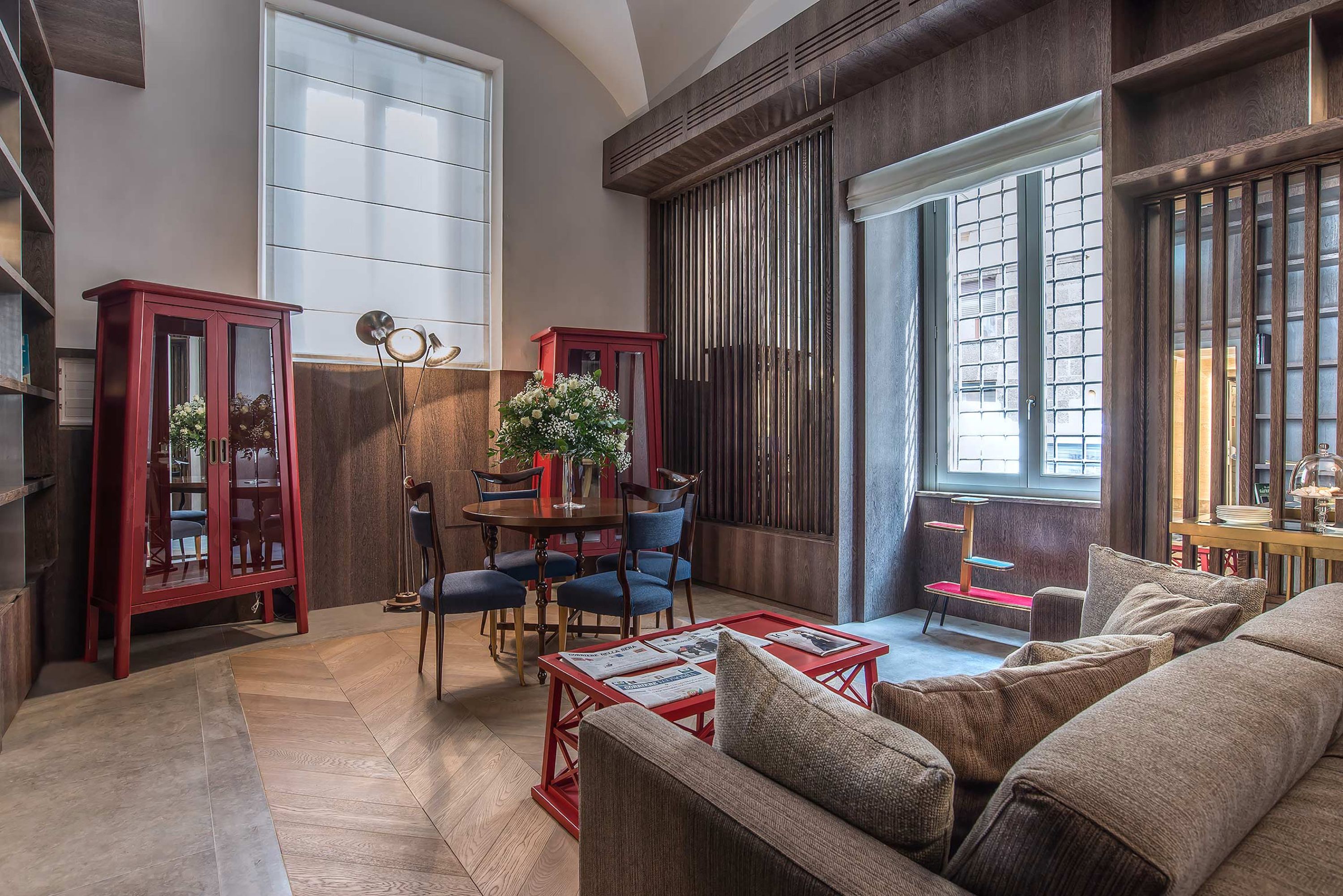 Un salón amplio con un ventanal grande, una zona de comedor con un aparador rojo y un rincón de estar acogedor con una mesa de centro roja.
