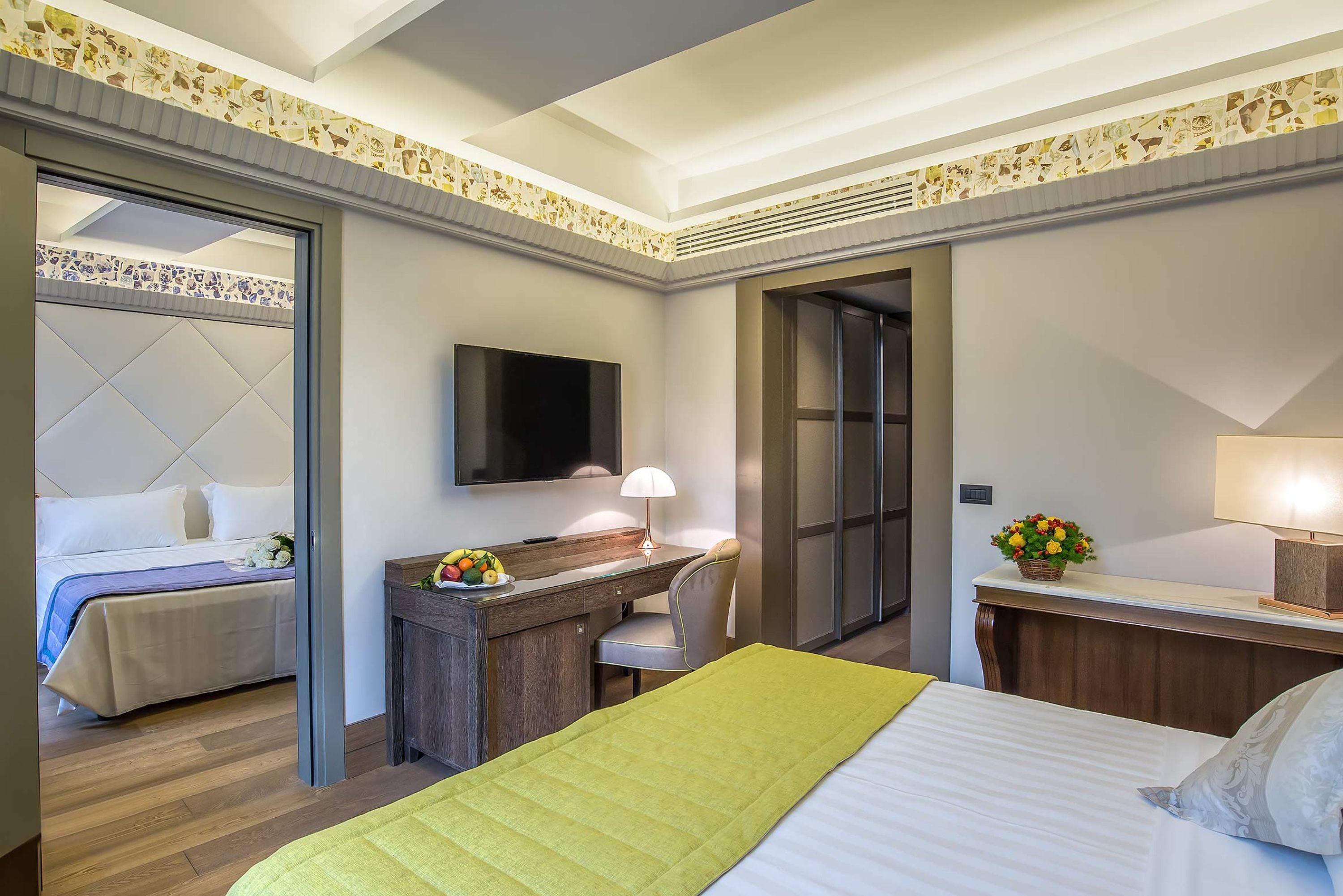 A hotel room with a bed, a desk, a chair, a TV, and a bathroom.