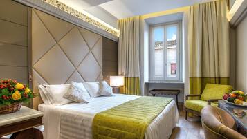 Habitación de hotel con cama, escritorio con lámpara, silla y ventana con cortinas.