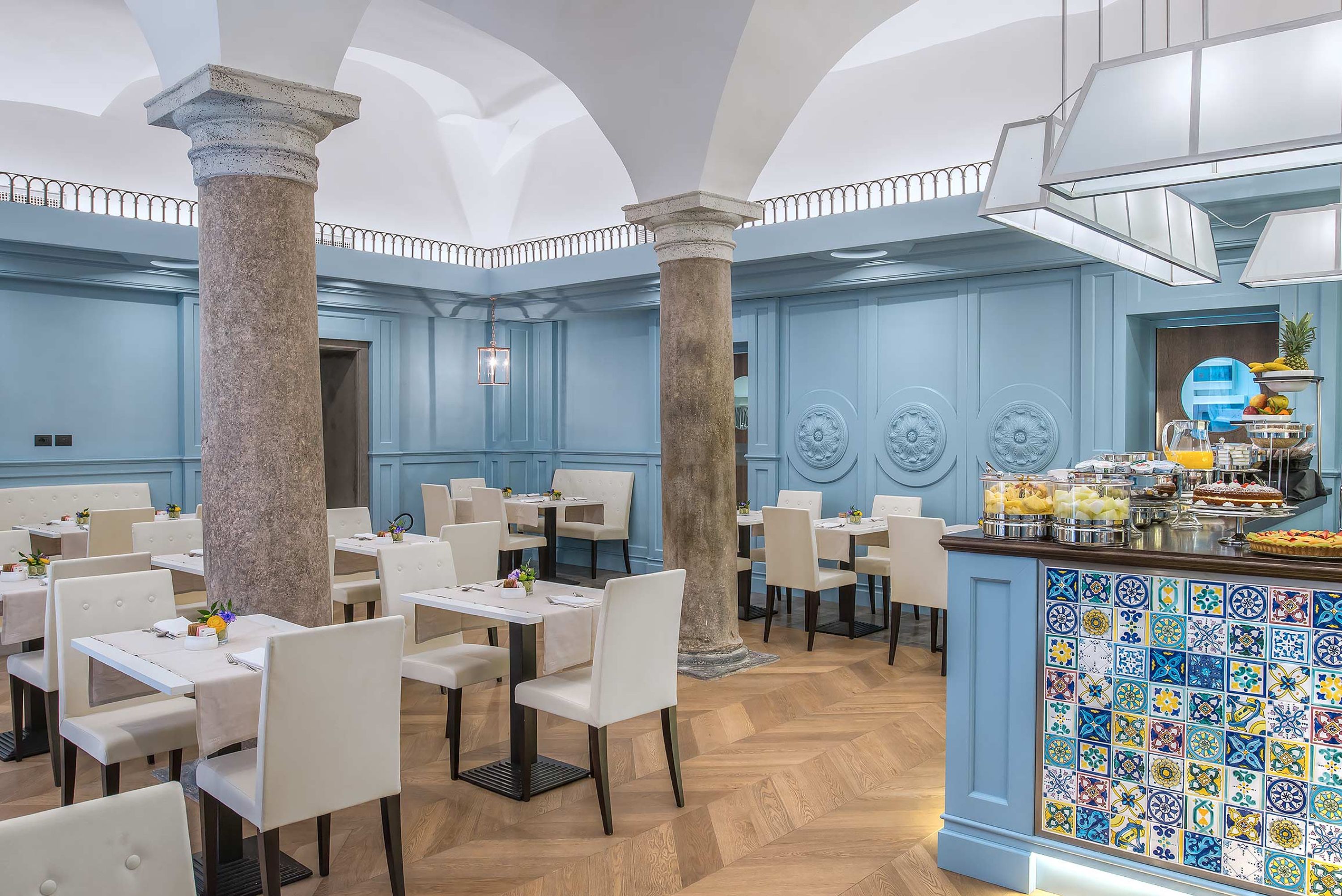A restaurant with blue walls, white chairs, and a tiled bar area.