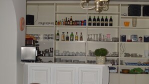 Una zona de bar con armarios blancos, una araña y taburetes.