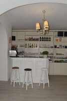 Una zona de bar con armarios blancos, una araña y taburetes.