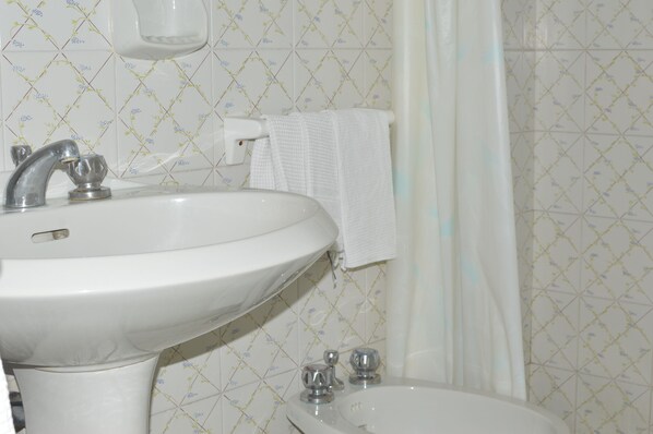 Un baño con un lavamanos blanco, un espejo y una cortina de ducha.