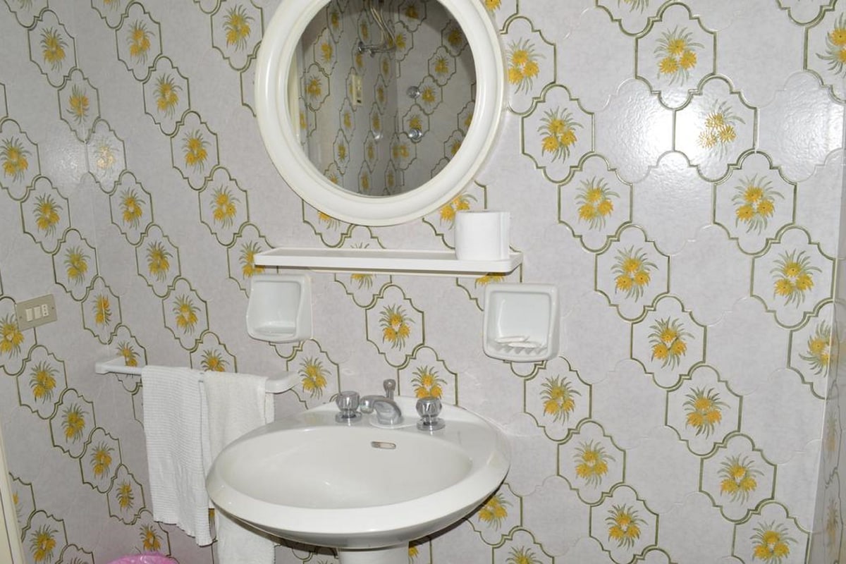 Une salle de bain avec un lavabo blanc, un miroir et un porte-serviettes.