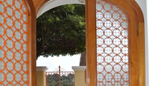 Una puerta de madera con un panel de vidrio, que da a un área vallada con un árbol al fondo.