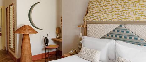Quarto bem arrumado com cama, almofadas, mesa de cabeceira, abajur, cadeira e relógio de parede.