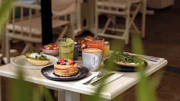 Una mesa de desayuno con diversos platos, como tortitas, ensalada y bebidas.