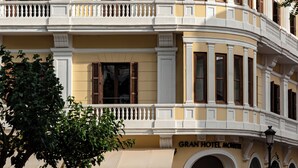 Ein mehrstöckiges Hotel mit gelber Fassade, weißen Balkonen und gewölbten Fenstern.