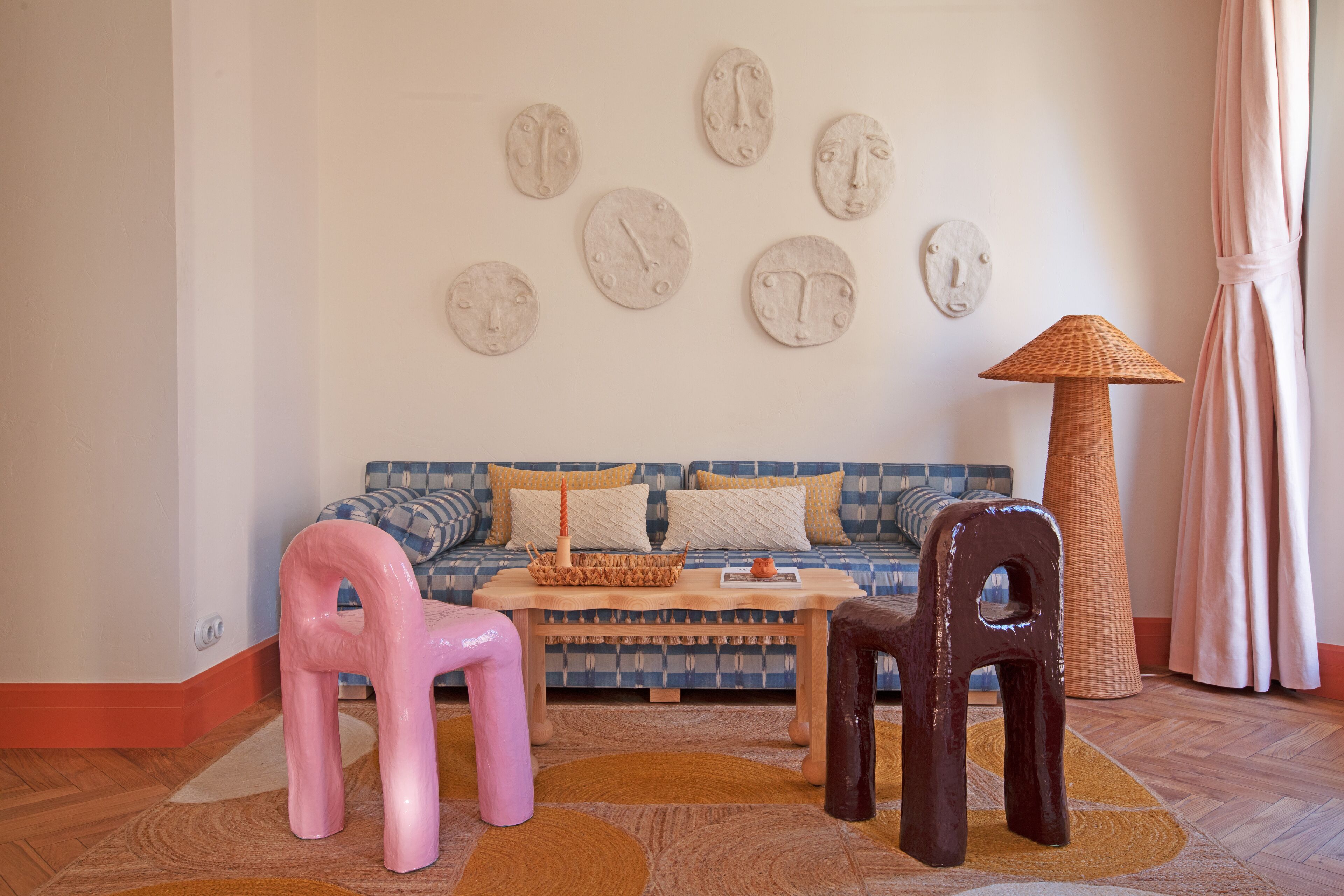 A living room with a patterned sofa, two chairs, a coffee table, and wall art.