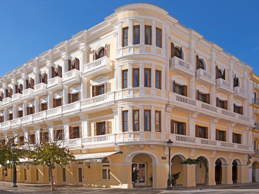 A multi-story hotel with balconies, arched doorways, and a classic architectural style.