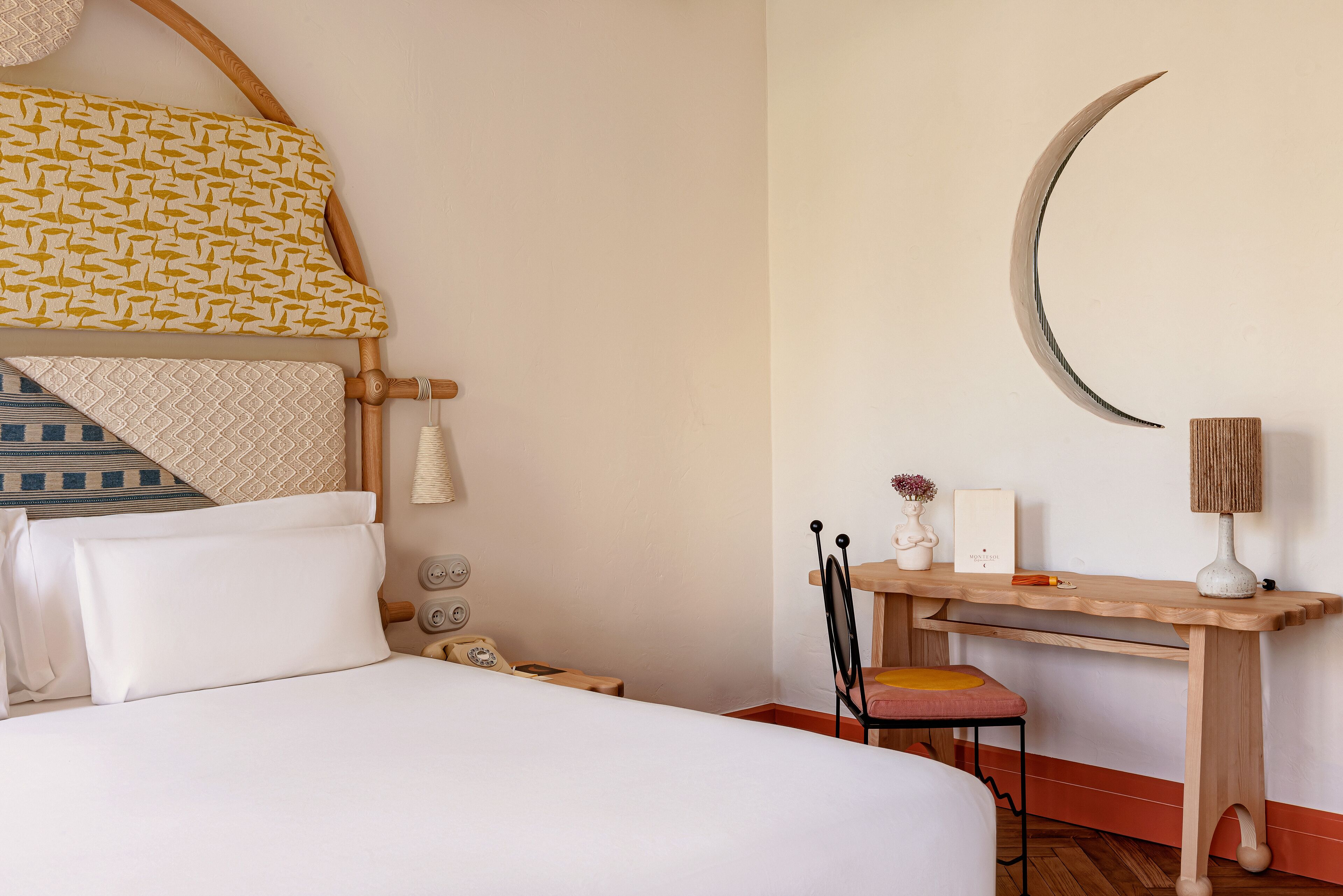 Une chambre bien rangée, avec un lit, une table de chevet, une chaise et un bureau doté d’une lampe.
