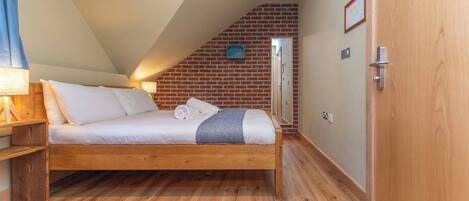 Een slaapkamer met een houten bed, een bakstenen muur en een deur.