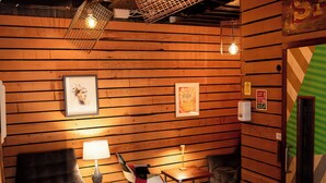 Une pièce chaleureuse avec des murs en bois, un fauteuil vert, une petite table avec une lampe et un luminaire suspendu.