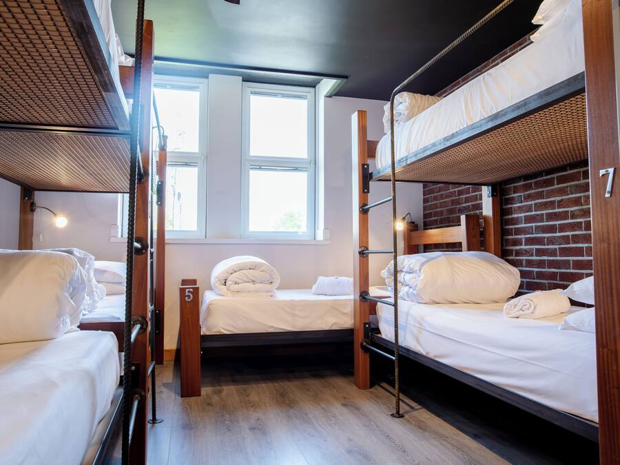 A dormitory room with bunk beds, a window, and a door.