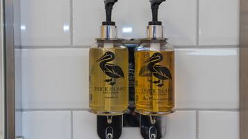 Dos botellas de champú y gel de ducha Two Duck Island montadas en una pared de azulejos.