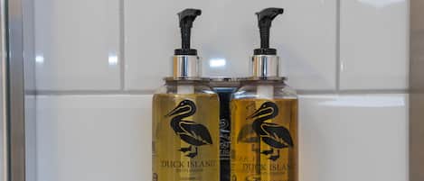 Dos botellas de champú y gel de ducha Two Duck Island montadas en una pared de azulejos.