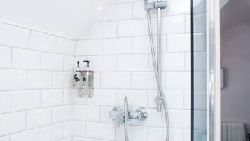A shower with a glass door, white tiled walls, and a visible towel rack.