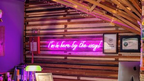 Un comptoir d'accueil avec un panneau néon, des poutres en bois et une lampe de bureau.