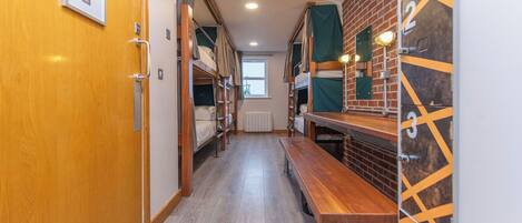 A corridor with bunk beds and a wooden bench.
