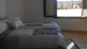 Een slaapkamer met een bed, kussens, een raam en een airconditioning.