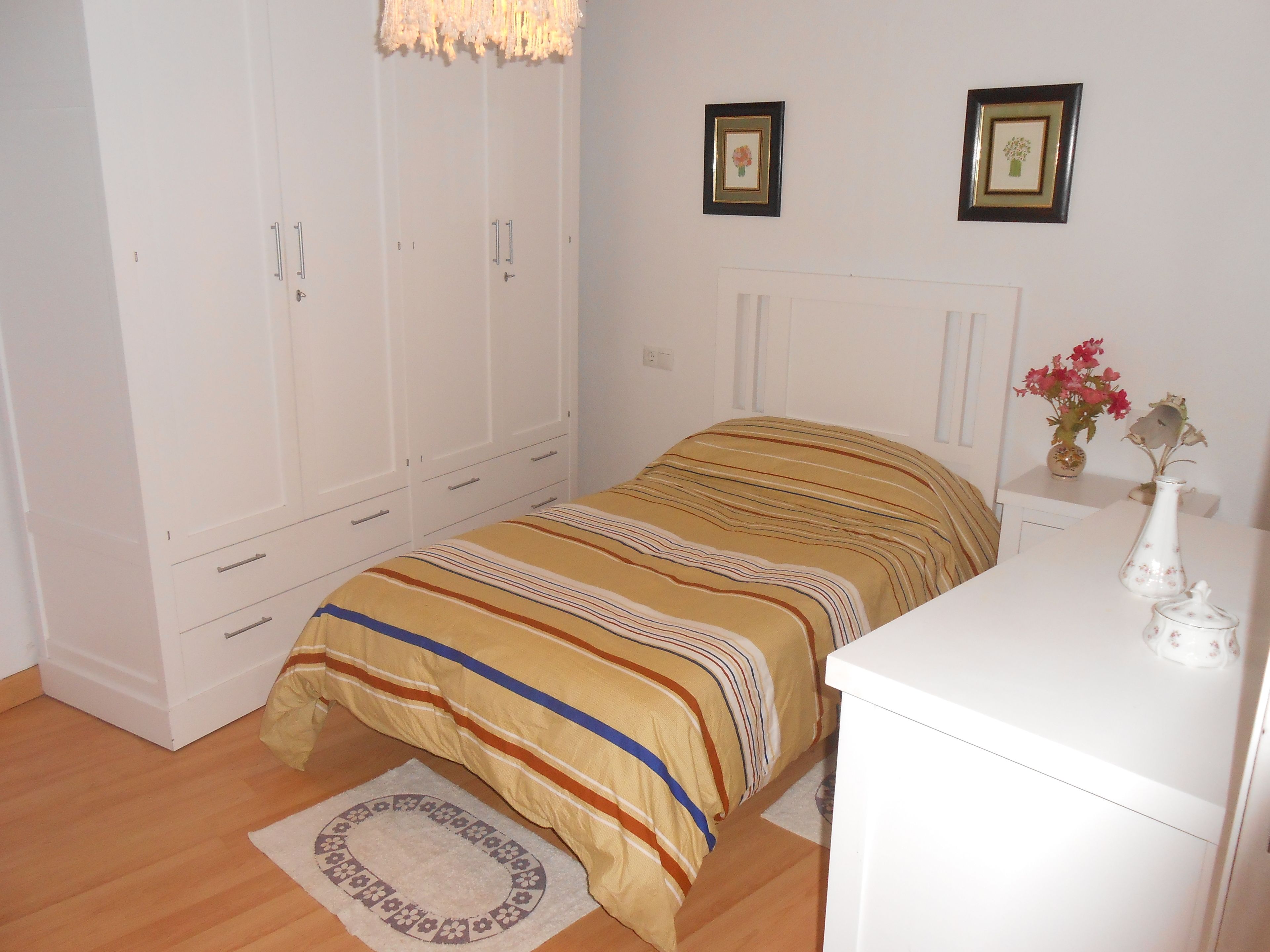 Ein Schlafzimmer mit Bett, Kleiderschrank, Nachttisch und kleinem Schreibtisch.