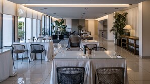 Un comedor moderno con mesas de vidrio, sillas de mimbre y amplios ventanales con vistas al exterior.