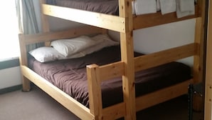 A bunk bed room with a carpeted floor and a window with curtains. - The School House Inn (Altmar)
