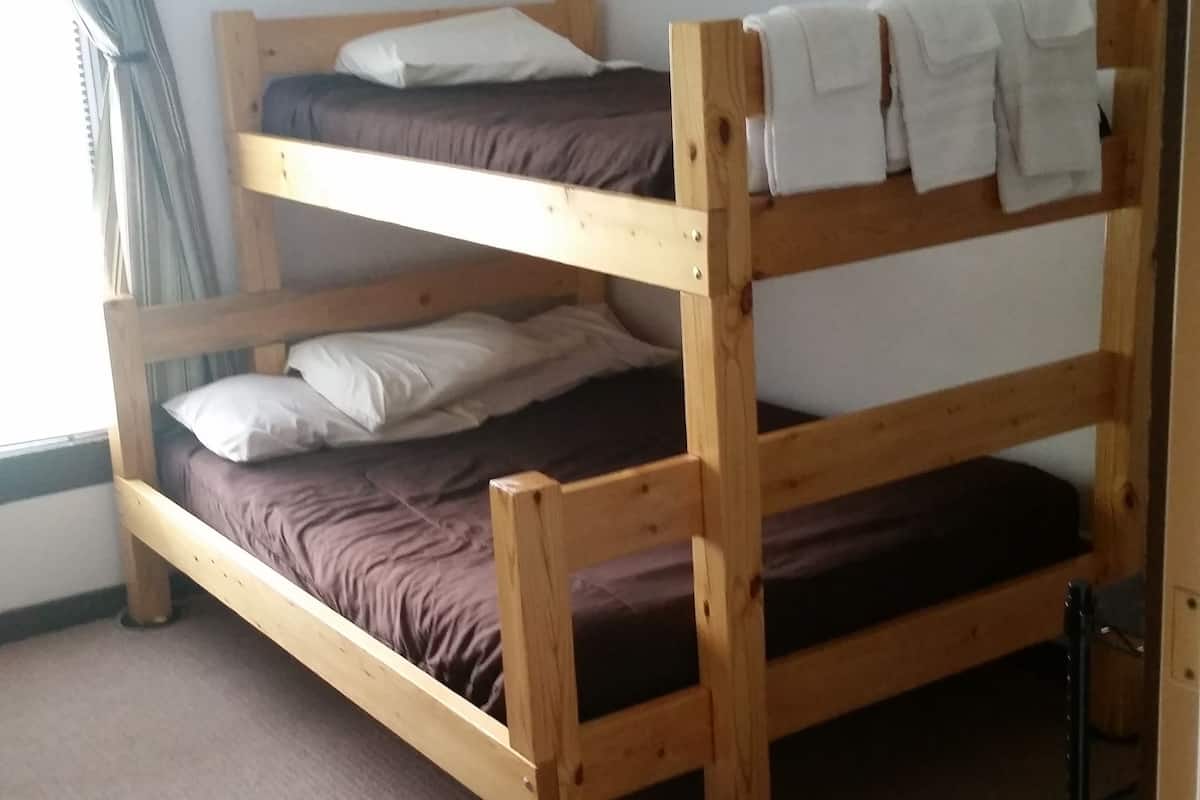 A bunk bed room with a carpeted floor and a window with curtains.