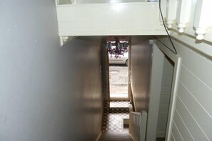 Un estrecho pasillo con piso estampado que lleva a una puerta.