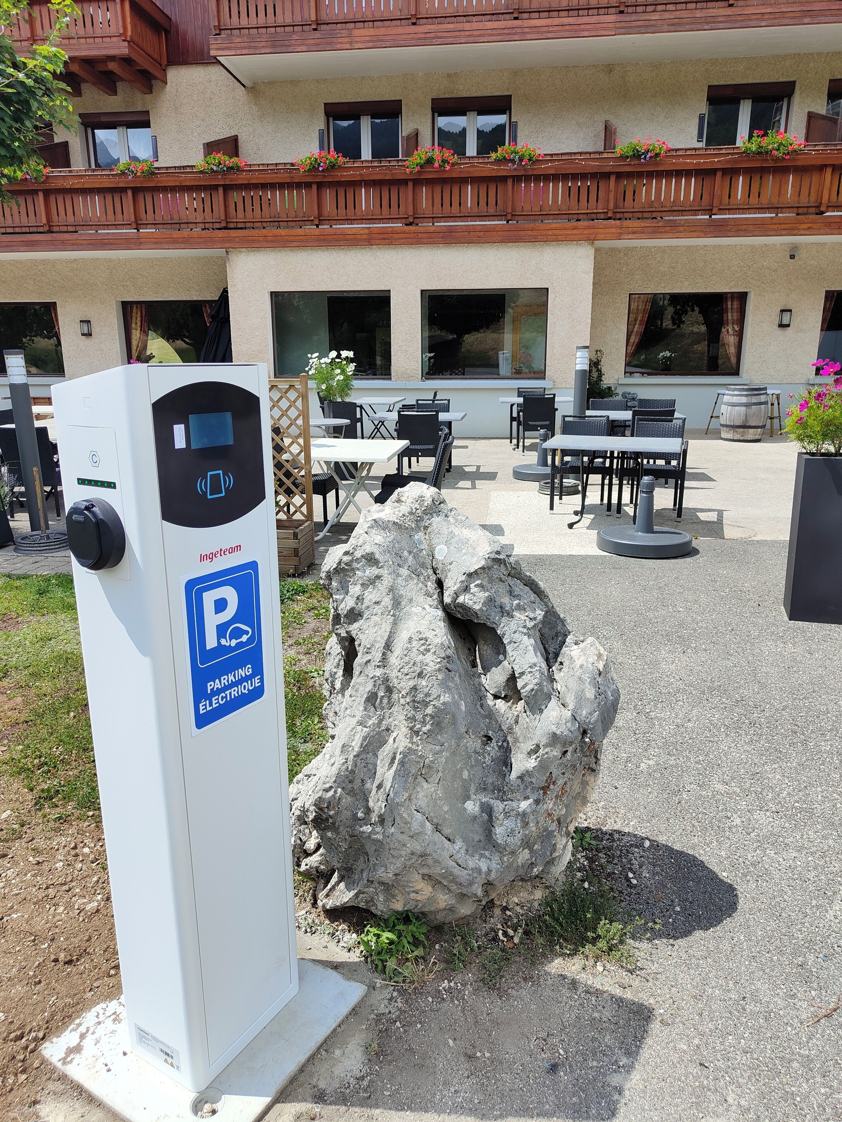 An outdoor area with a parking meter, outdoor seating, and a building with balconies.