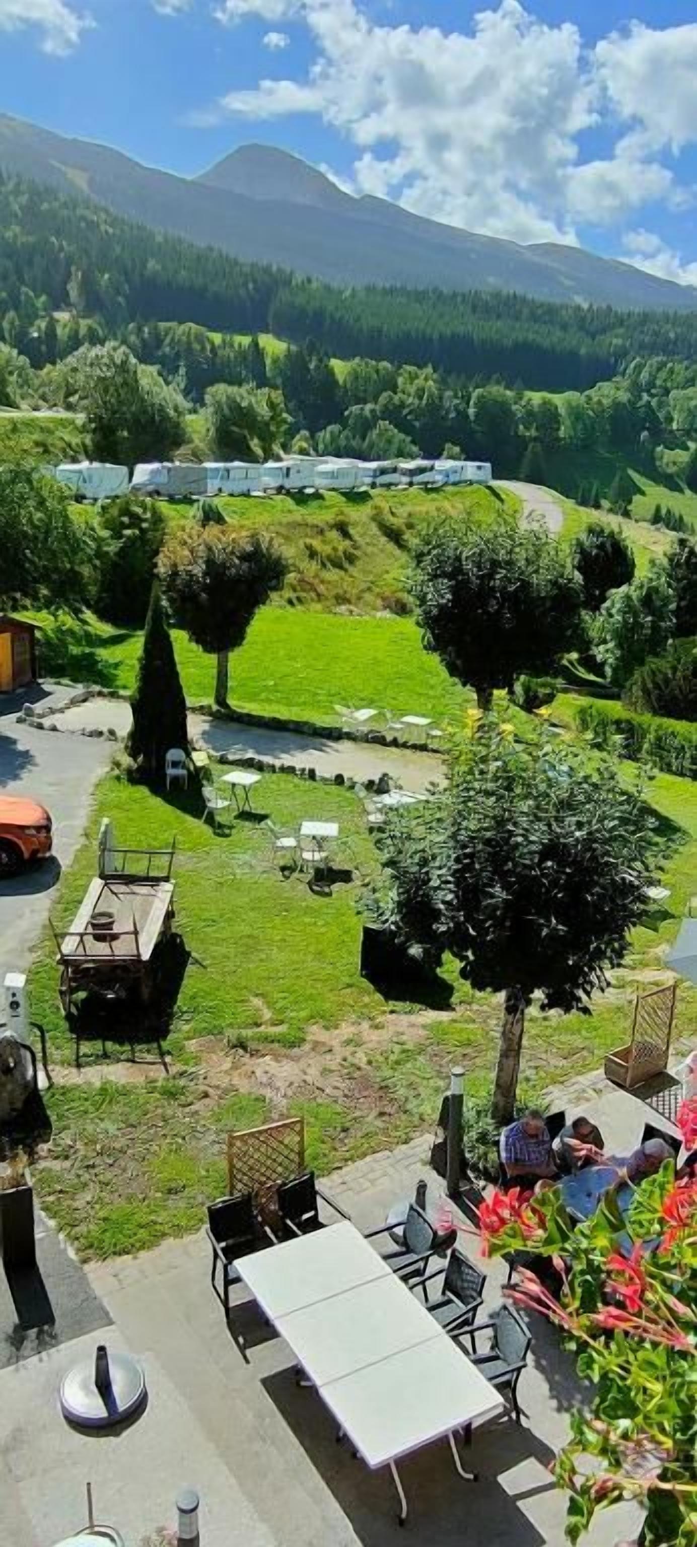 A campsite with outdoor seating, a barbecue area, and a view of the surrounding hills.