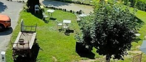 A campsite with outdoor seating, a barbecue area, and a view of the surrounding hills.