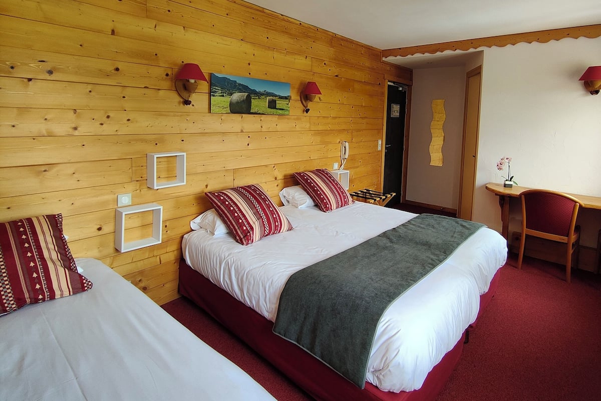 Ein Hotelzimmer mit zwei Betten, Holzwandverkleidung, einem Gemälde und einem Schreibtisch mit Stuhl.