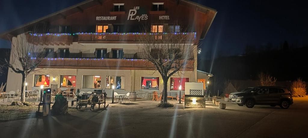 Un bâtiment abritant un restaurant et un hôtel, avec une terrasse et un espace de stationnement.