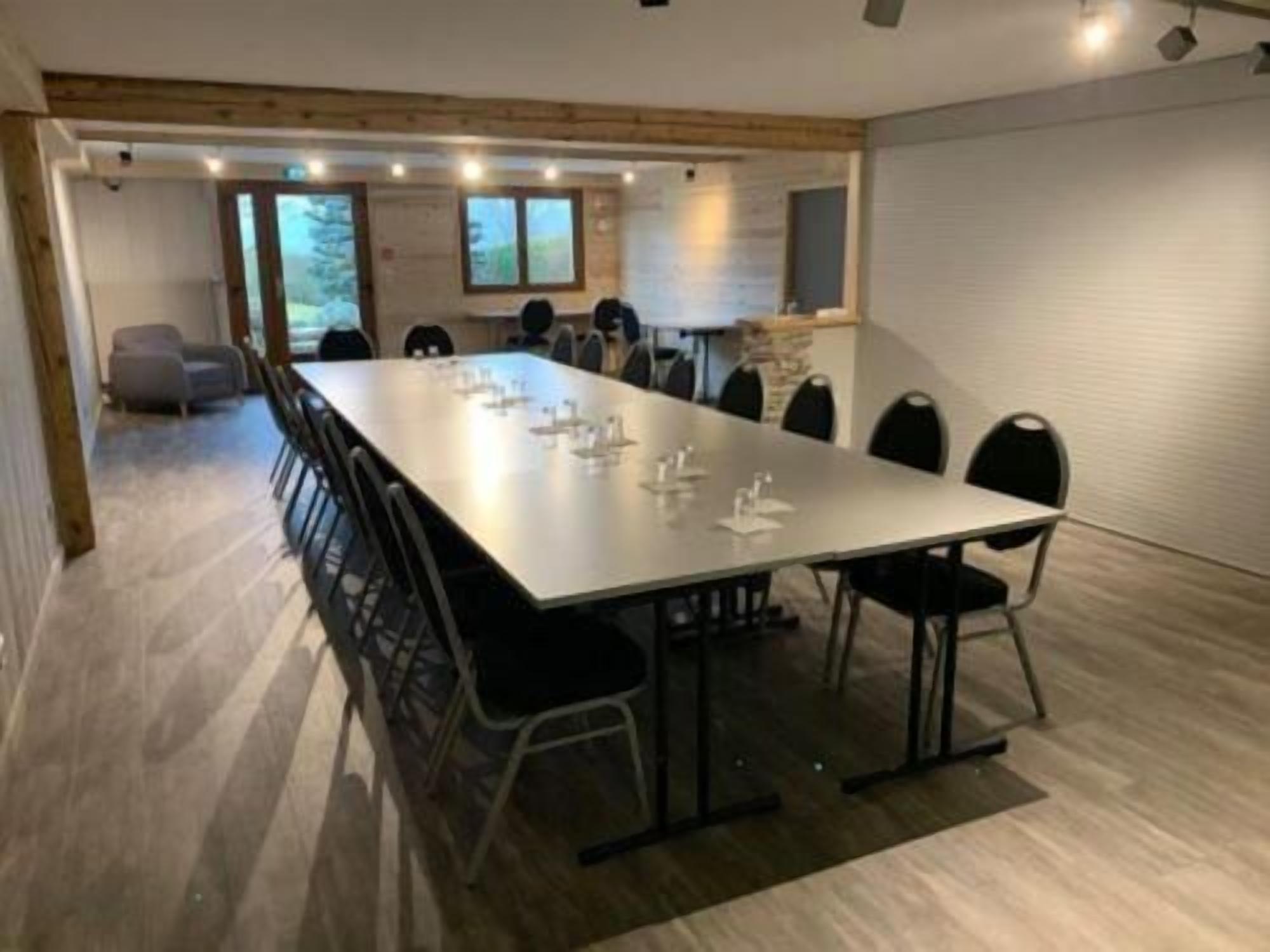 Une salle de conférence avec une longue table et des chaises, un plafond en bois et une vue sur l’extérieur.