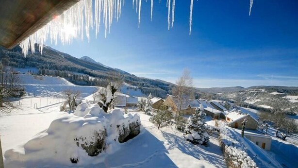 A snowy landscape with houses and mountains in the background.