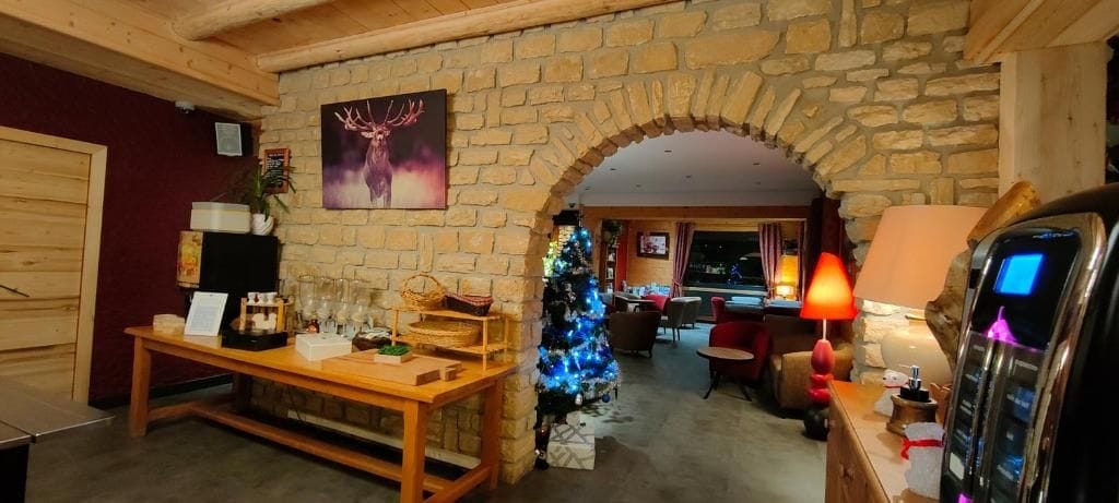 Una habitación acogedora con pared de piedra, un banco de madera, un árbol de Navidad y una chimenea.