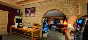 A cozy room with a stone wall, a wooden bench, a Christmas tree, and a fireplace. - Hôtel les Playes (Villard-de-Lans)