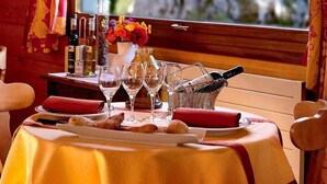 A table set for dining with wine glasses, a basket of bread, and a bottle of wine.