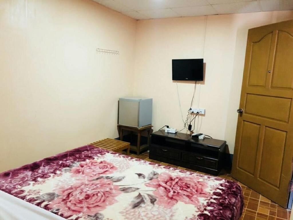 A bedroom with a bed, a television, a dresser, and a door.
