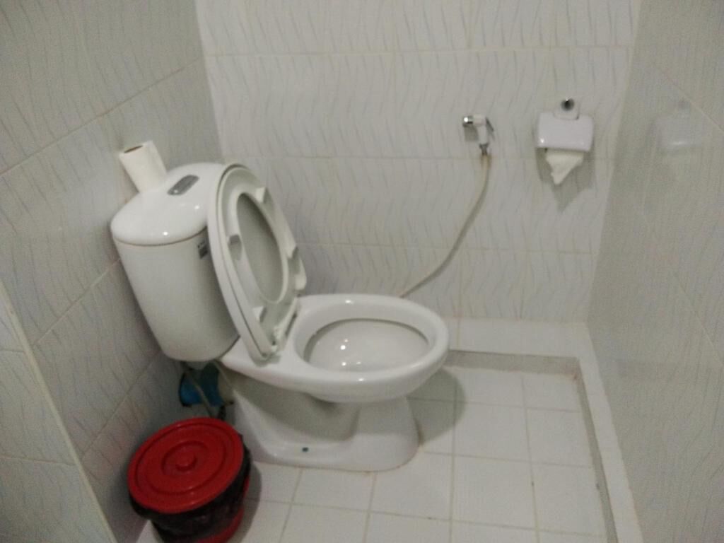 A standard bathroom with a toilet, a bidet, and a red trash bin.
