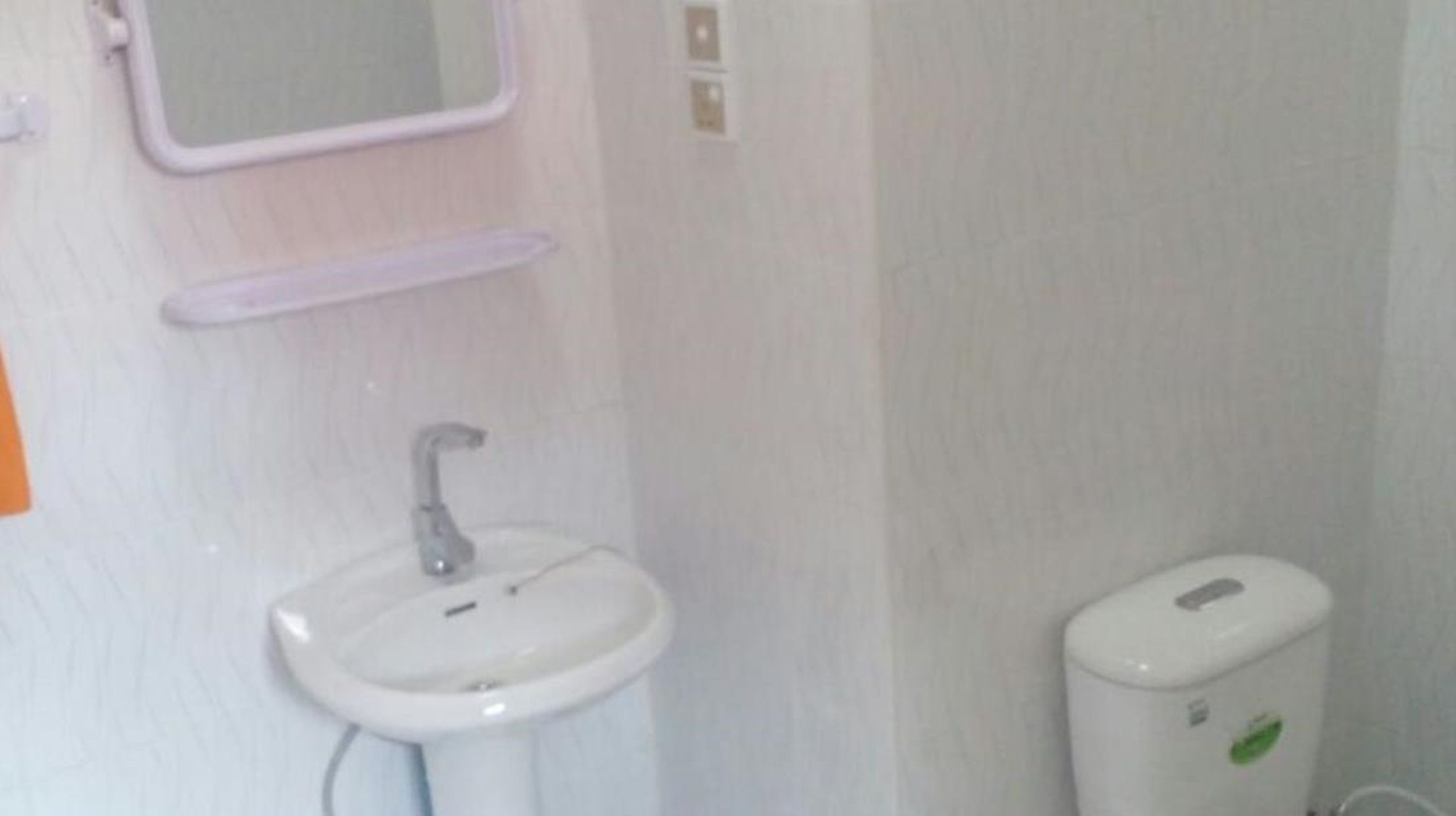 A bathroom with a white sink, a mirror, and a trash bin.