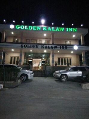 De buitenkant van Golden Kalaw Inn, met een opvallend bord en een goed verlichte ingang.
