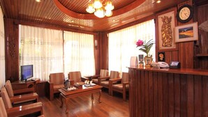 Un vestíbulo con piso de madera, un mostrador de recepción, varias sillas, una mesa de centro y un televisor.