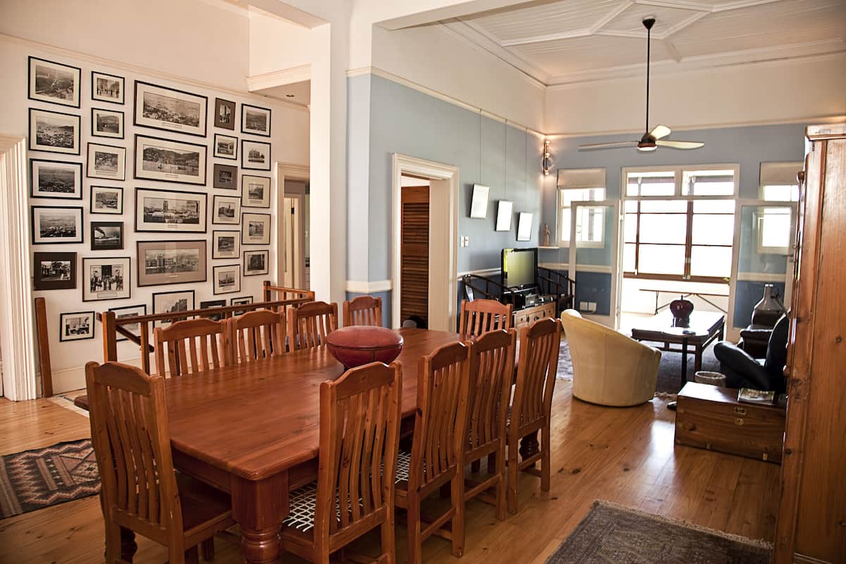 A spacious dining area with a large wooden table and chairs, surrounded by walls adorned with framed photographs.