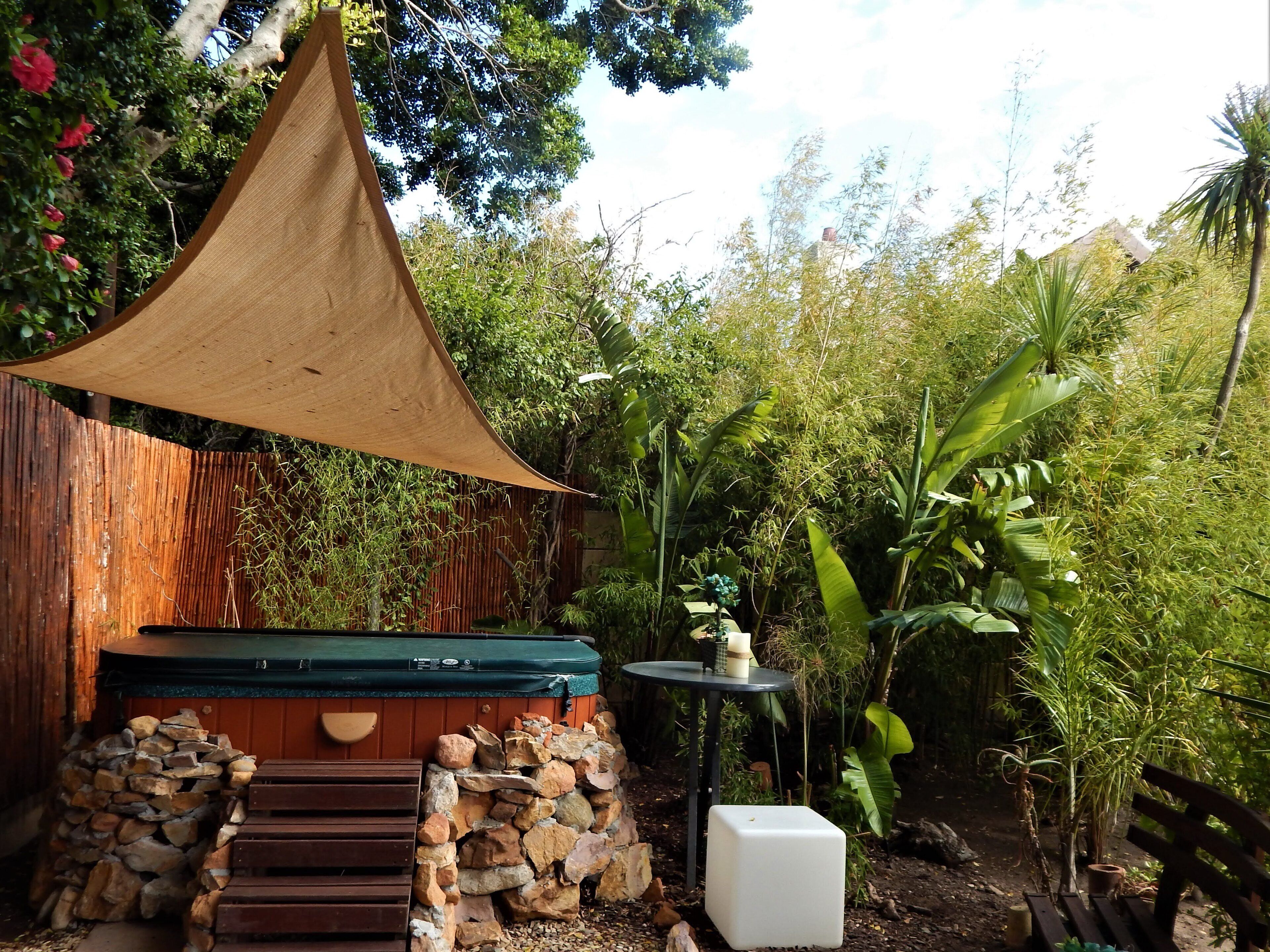 A wooden outdoor seating area with a barbecue grill, a stone wall, and a table with a small plant.