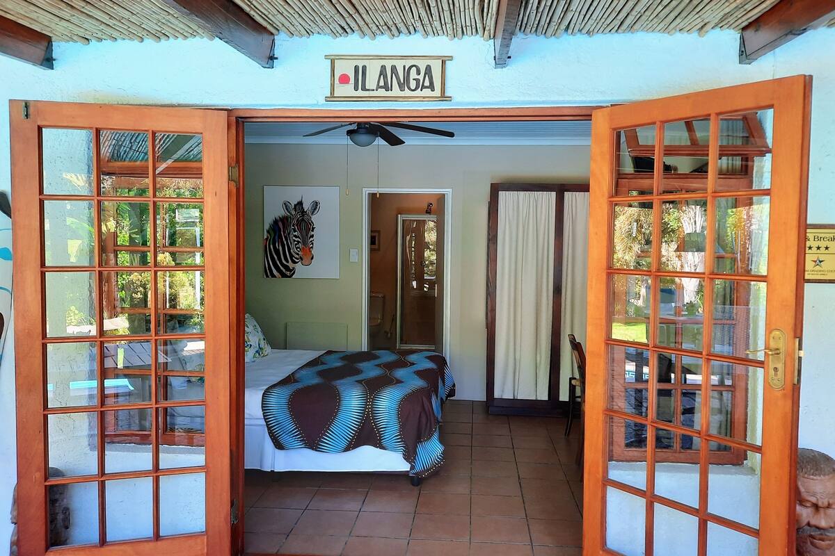 A room with a bed, a zebra painting, and a sign reading "ILANGA".